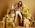 Smiling woman standing among 2 piles of golden gifts