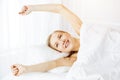 Smiling woman stretching hands in bed after waking up, entering a day happy and relaxed. Sweet dreams, sunny morning Royalty Free Stock Photo