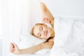 Smiling woman stretching hands in bed after waking up, entering a day happy and relaxed. Sweet dreams, sunny morning Royalty Free Stock Photo