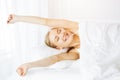 Smiling woman stretching hands in bed after waking up, entering a day happy and relaxed. Sweet dreams, sunny morning Royalty Free Stock Photo