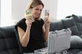 Smiling woman with suitcase full of money holding stacks of dollar bills and looking at camera. Royalty Free Stock Photo