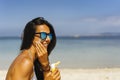 Smiling woman with sunglasses applying sun protection cream on her face in the beach Royalty Free Stock Photo