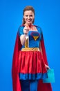 smiling woman in superhero costume with rag and detergent in hands