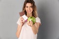 Smiling woman in t-shirt holding chocolate and giving fresh apple