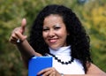 Smiling woman with a tablet showing thumb up, outdoor.