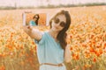 Smiling woman taking a photo selfie with smartphone in flowers field.