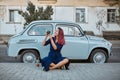 Smiling woman taking picture on photocamera. Old fashioned blue car. Time to travel, new emotion and new place concept