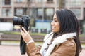 Smiling woman taking pictures with camera in the street. Royalty Free Stock Photo