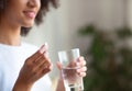 Smiling woman taking white round pill, holding water glass in hand Royalty Free Stock Photo