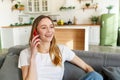 Smiling woman talking on the phone while laughing. Young cheerful lady having fun during a funny conversation call at home Royalty Free Stock Photo