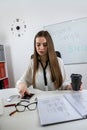 Smiling woman teacher sitting at desk with laptop and explaining grammar rules near whiteboard Royalty Free Stock Photo