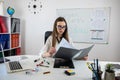 Smiling woman teacher sitting at desk with laptop and explaining grammar rules near whiteboard Royalty Free Stock Photo