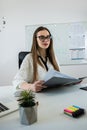 Smiling woman teacher sitting at desk with laptop and explaining grammar rules near whiteboard Royalty Free Stock Photo