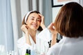 Smiling woman touching face wearing housecoat before mirror