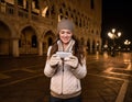 Smiling woman tourist writing sms on St. Marks Square, Venice Royalty Free Stock Photo