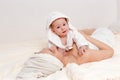 A smiling woman with a towel on her head and a baby girl in a Bathrobe lie on the bed after bathing Royalty Free Stock Photo