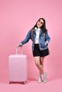 Smiling woman traveler holding pink suitcase and passport document over pink background. Royalty Free Stock Photo