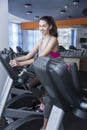 Smiling woman on a treadmill in the gym. Beautiful young brunette in sportswear. Activity, sport and healthy lifestyle. Vertical Royalty Free Stock Photo