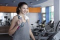 Smiling woman on treadmill with water bottle and towel at the gym. Beautiful young brunette in sportswear. Activity, sport and Royalty Free Stock Photo