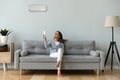 Smiling woman using air conditioner remote controller, sitting on couch Royalty Free Stock Photo