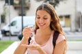 Smiling woman using antibacterial hand sanitizer in city street. Young woman washing hands with alcohol gel or antibacterial soap