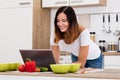 Smiling Woman Using Laptop In Kitchen Royalty Free Stock Photo