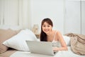 Smiling woman using a laptop while lying on her bed Royalty Free Stock Photo