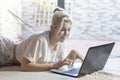 Smiling woman using a laptop while lying on her bed Royalty Free Stock Photo