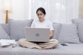 Smiling woman using laptop sitting on couch at home. Women sitting on sofa use laptop shopping, chat online on social network. Royalty Free Stock Photo