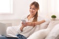 Woman Using Mobile Phone And Laptop Sitting On Couch Indoor