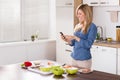 Smiling Woman Using Mobilephone In Kitchen