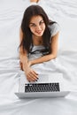 Smiling woman using a notebook on her bed Royalty Free Stock Photo