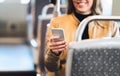 Smiling woman using smartphone in train, subway, bus or tram