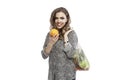 Smiling woman with vegetables in eco bag. Beautiful blonde woman in black leggings and a leopard print shirt with an orange in her Royalty Free Stock Photo