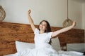 Smiling woman waking up happy after healthy sleep stretching on comfortable bed, rested refreshed girl enjoys pleasant wakeup