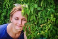 Smiling woman on a warm day near ivy. Woman face close-up against the wall of green loach. Summer portrait of a brunette girl with Royalty Free Stock Photo