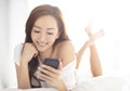 smiling woman watching mobile phone on bed Royalty Free Stock Photo
