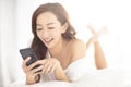 smiling woman watching mobile phone on bed Royalty Free Stock Photo