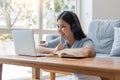 Smiling woman watching video using laptop, relaxing on a couch at home in the living room Royalty Free Stock Photo