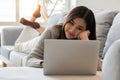 Smiling woman watching video using laptop, relaxing on a couch at home in the living room Royalty Free Stock Photo