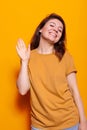Smiling woman waving with palm at camera in studio