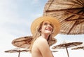 Smiling woman wear sun straw hat under beach umbrella of straw concept of summer beach holiday, vacation travel or sun skin care Royalty Free Stock Photo