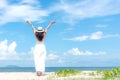 Smiling woman wearing fashion white dress summer walking on the sandy ocean beach, beautiful blue sky background. Happy woman enj Royalty Free Stock Photo