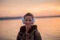 Smiling woman wearing fluffy ear muffs at sunset