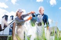 Smiling woman wearing peaked cap joining her husband watering plants