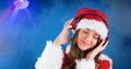 Smiling woman wearing Santa hat while listening music against blue background Royalty Free Stock Photo