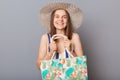 Smiling woman wearing striped swimming suit and sun hat looks relaxed and happy, enjoying a peaceful vacation by the beach, Royalty Free Stock Photo