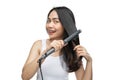 a smiling woman wearing underdress uses a hair straightener to straighten Royalty Free Stock Photo