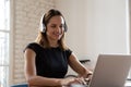 Woman wearing headphones working typing on notebook enjoy e-learning process