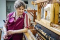 Smiling woman weaver working on loom manufacturing whool shawl clothing.